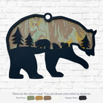 The Rustic Rhode’s DIY Paint Pour- Bear in a Forest is a bear-shaped wooden art piece with marbled earth-tone paint, forest tree, and bear cub cut-outs. Paint swatches underneath show custom color options.